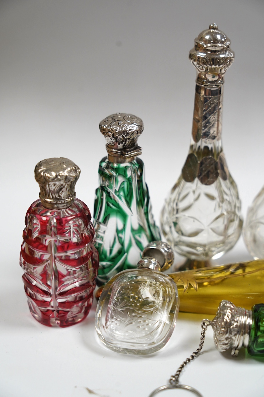 A collection of ten assorted Victorian and later silver or white metal mounted glass scent bottles, including teardrop shaped by Saunders & Shepherd, Birmingham, 1884, 12.7cm. Condition - poor to fair to good